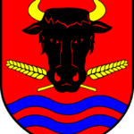 Herb przedstawia czarną głowę byka, łodygi pszenicy i faliste niebieskie paski na czerwonym tle.