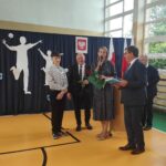 Uroczystość wręczenia nagród podczas zakończenia roku szkolnego w szkole w Będzinie. Uczniowie i władze szkoły świętują osiągnięcia naukowe.