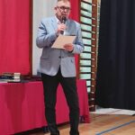 Mężczyzna w garniturze przemawiający na uroczystości zakończenia roku szkolnego w szkole w Będzinie.