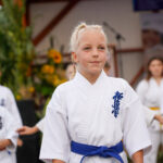 Młoda dziewczyna w karate gi z niebieskim pasem w Dożynkach Gminne Tymień.