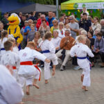 Występ dzieci w karate w Dożynkach Gminnych Tymień 2025. Demonstrację oglądają widzowie.