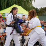 Pokaz karate w Dożynkach Gminne Tymień 2025. Dwie kobiety w białych gisach.