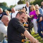 Zawody w przeciąganiu liny w Dożynkach Gminne Tymień 2025. Zawodnicy męczą się z wysiłkiem.