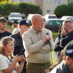 Tłum w Dożynkach Gminne Tymień 2025 słuchający prelegenta z mikrofonem.