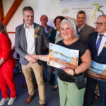 Uroczystość wręczenia nagród w Dożynkach Gminne Tymień 2025. Kobieta otrzymuje bon o wartości 500 zł.