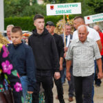 Dożynki Gminne Tymień 2025: Pochód osób niosących udekorowane snopki pszenicy i tablice z napisami „Solectwo Smolne” i „Solectwo Stoisław”.