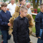 Chłopcy niosący krzyż z dożynkową aranżacją podczas obchodów Tymienia 2025.