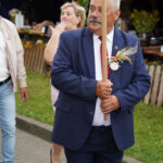 Mężczyzna w garniturze niesie laskę w Dożynkach Gminne Tymień.
