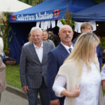 Goście Dożynek Gminnych Tymień 2025 ubrani w garnitury i stroje smart casual.