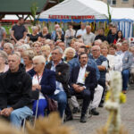 Uczestnicy Dożynek Gminnych Tymień 2025 siedzieli na zewnątrz.
