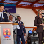 Urzędnicy Dożynki Gminne Będzino przemawiają na podium z logo Gminy Będzino.