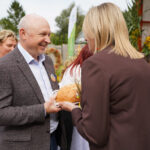 Urzędnicy wymieniają się bochenkiem chleba podczas uroczystości Dożynki Gminne Tymień 2025.