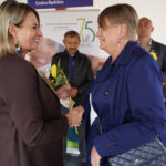 Dwie kobiety podające sobie dłonie na Dożynkach Gminnych Tymień 2025. Wymienia się słonecznikiem.