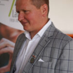 Mężczyzna w szarym garniturze w kratę w Dożynkach Gminne Tymień.