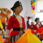Młoda osoba w stroju pirata z wachlarzem na występie.