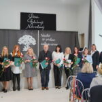Grupa osób podczas Dnia Edukacji Narodowej w Gminie Będzino, trzymających róże i dyplomy.