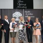 Grupowe zdjęcie z Dnia Edukacji Narodowej w Gminie Będzino. Osoby trzymają róże i dyplomy.